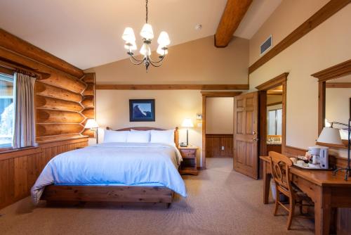 a bedroom with a bed and a table and a desk at Mike Wiegele Helicopter Skiing in Blue River