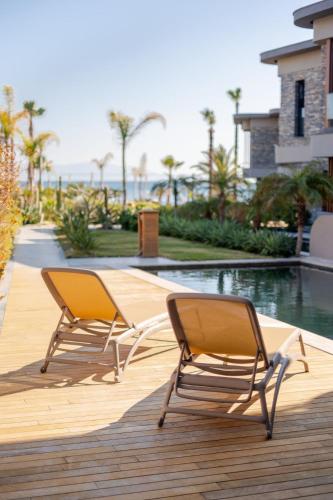 two chairs sitting on a deck next to a swimming pool at Luxurious Villa Private Pool Private Beach Views in Bodrum City