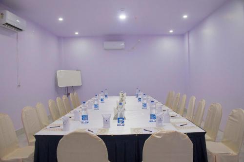 a long table in a room with white chairs at The Kannelite in Jamshedpur
