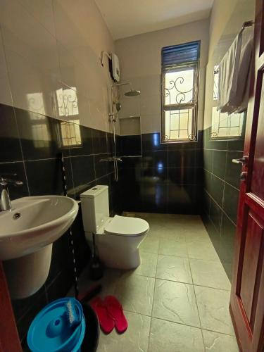 a bathroom with a toilet and a sink and a window at Vine Suites Mbarara - 1 Bed Studio Apartment Near LDC & City Centre - Quiet & Convenient in Mbarara