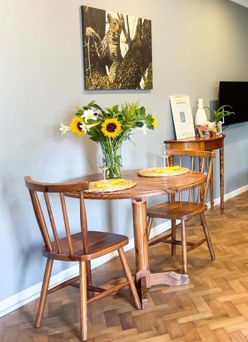 a wooden table with two chairs and a vase of flowers at Hilton Heath in Hilton