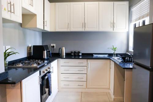 a kitchen with white cabinets and black counter tops at Hilton Heath in Hilton