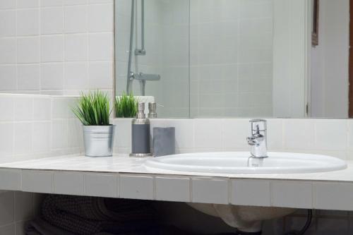 lavabo con grifo y espejo en For You Rentals Alfonso XIII Apartment, en Madrid