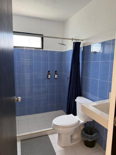 a blue tiled bathroom with a toilet and a shower at Casa Nora in Sisal