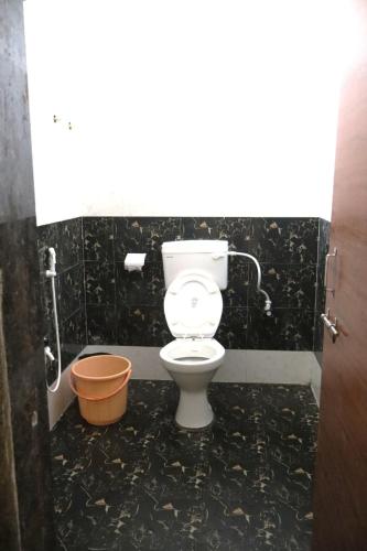 a bathroom with a toilet in a black tiled room at MMG Resorts in Nāspur