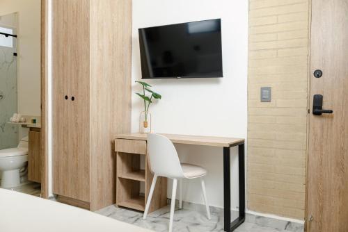 a room with a desk and a television on a wall at Foret Lofts in Medellín