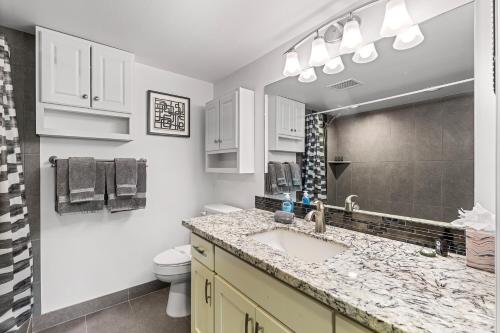 a bathroom with a sink and a toilet and a mirror at Kona Pacific E629: Beautifully Remodeled condo! in Kailua-Kona