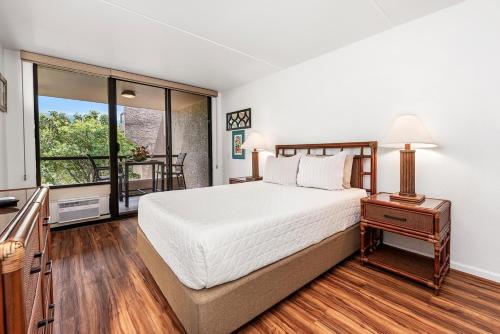 a bedroom with a large bed and a balcony at Kona Pacific E629: Beautifully Remodeled condo! in Kailua-Kona