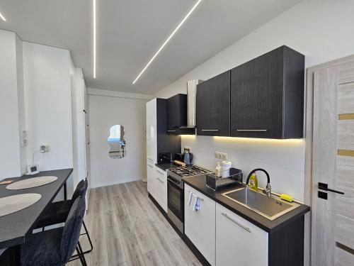 a kitchen with black and white cabinets and a table at Barcika Prémium Stúdió in Kazincbarcika
