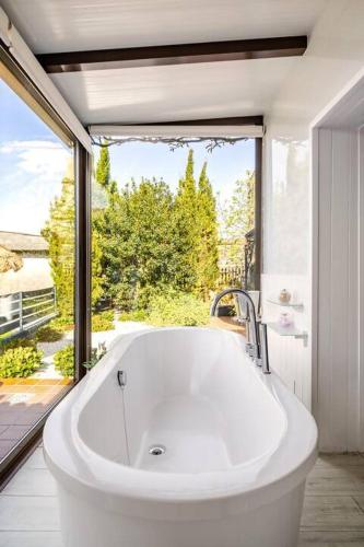 a large white bath tub in a bathroom with a window at Mar no Camiño. Terraza, bañera con vista al mar. in Brens