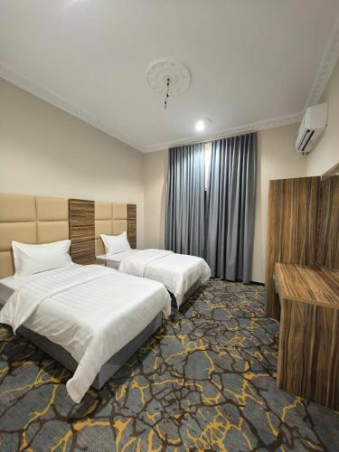 a hotel room with two beds and a television at شقــق فندقيـة in Hail