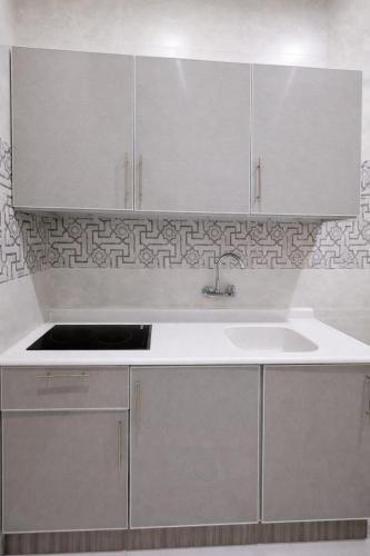a kitchen with white cabinets and a sink at شقــق فندقيـة in Hail