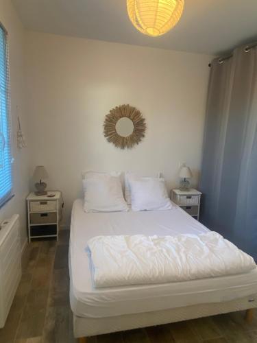 a bedroom with a white bed with a mirror on the wall at Le sable chaud in Saint-Pierre-dʼOléron