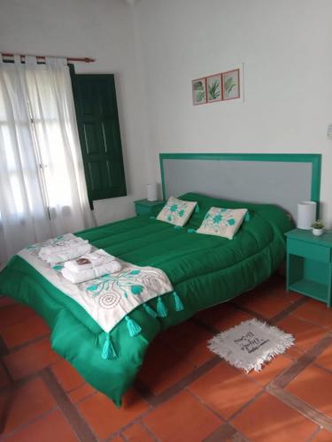 a bedroom with a green bed with towels on it at Hospedaje El Rincon in San Antonio de Areco