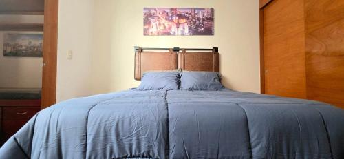 a bed with a blue comforter in a bedroom at 3BR Sn Rafael CDMX metro, mercado, Reforma, Zócalo in Mexico City