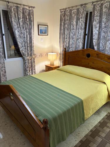 a bedroom with a wooden bed with a green blanket at Villa Filip Coral Bay in Peyia