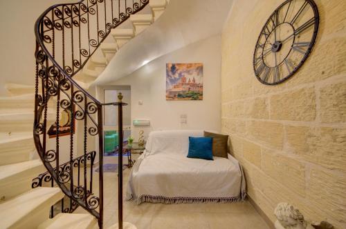 a bedroom with a bed and a large clock on the wall at Suite Victory Authentic Maltese Duplex in Birgu in Birgu