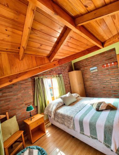 a bedroom with a bed and a wooden ceiling at Cabañas Tunquelen in El Bolsón