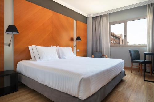 a hotel room with a large bed and a window at Dorma Juan de Austria in Valladolid