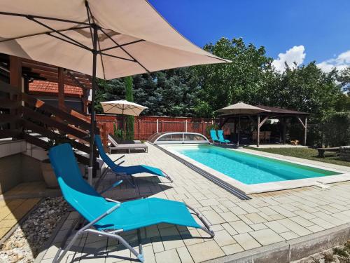 a swimming pool with blue chairs and an umbrella at Kovács Apartmanház in Balatonfüred