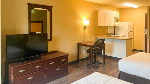 a hotel room with a television on a dresser with a desk at Studio 6 Chantilly VA Washington Dulles Airport in Chantilly
