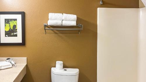 a bathroom with a toilet and towels on a wall at Studio 6 Chantilly VA Washington Dulles Airport in Chantilly