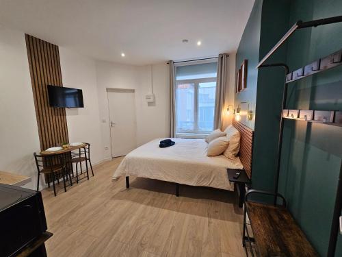 a bedroom with a bed and a table and a television at LD Atmosphère in Saint-Quentin