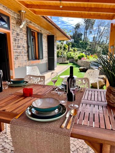 a wooden table with plates and a bottle of wine at Casa Flor do Monte in Funchal