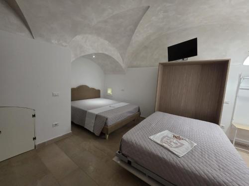 a bedroom with two beds and a flat screen tv at La suite del Marchese a Vieste in Vieste