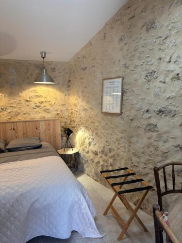 a bedroom with a bed and a stone wall at l'atelier by Emma in Bommes