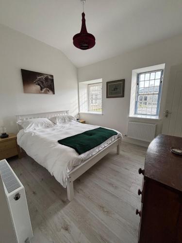a bedroom with a white bed and two windows at Carpenters Cottage in Rathvilly