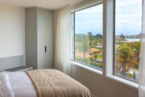 a bedroom with a bed and a large window at The Sea Breeze in Timaru