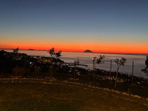 a sunset over the ocean with a fence and trees at Casa Natura 40 in Parghelia