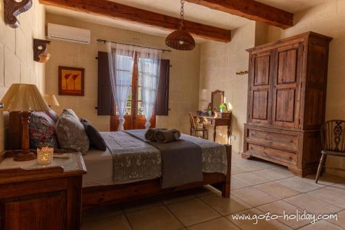 a bedroom with a bed and a dresser in a room at Ta Lilly Xaghra in Xagħra