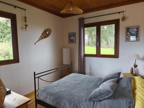 a bedroom with a bed and two windows at Le chalet de Maryvonne in Gibles