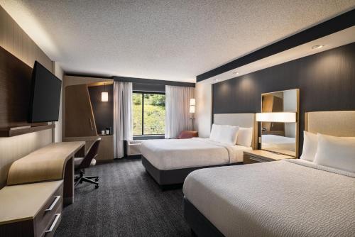 a hotel room with two beds and a television at Courtyard by Marriott Wilkes-Barre Arena in Wilkes-Barre