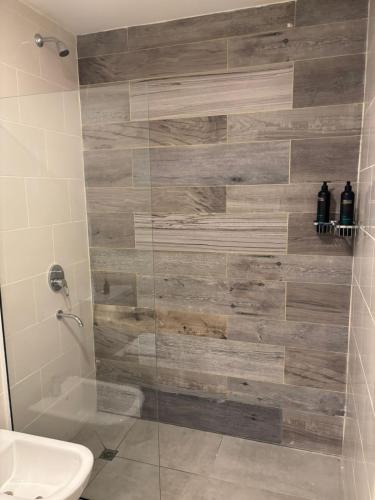 a bathroom with a shower with a wooden wall at Altamar a metros del Hospital Regional y Cabin in Comodoro Rivadavia