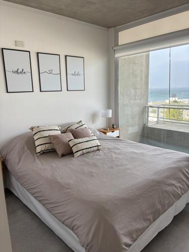a bedroom with a large bed with a large window at Altamar a metros del Hospital Regional y Cabin in Comodoro Rivadavia