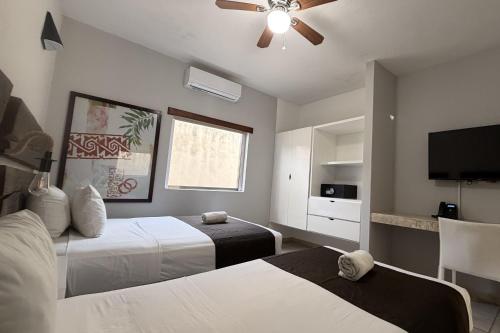 a bedroom with two beds and a flat screen tv at Days Inn by Wyndham Playa del Carmen in Playa del Carmen