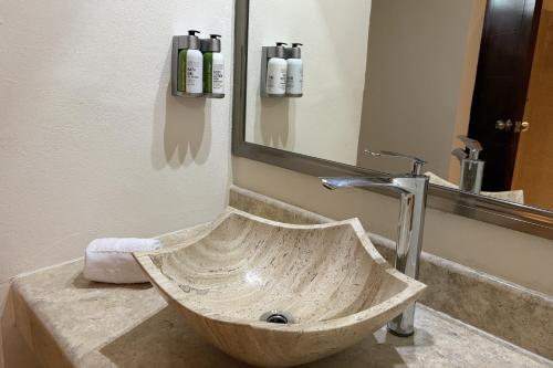 a stone sink in a bathroom with a mirror at Days Inn by Wyndham Playa del Carmen in Playa del Carmen