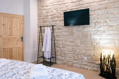 a bedroom with a stone wall with a bed and a television at OPG Kuzmanović in Goljak