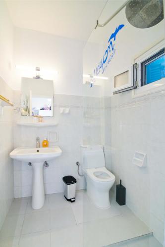 a white bathroom with a toilet and a sink at Alkyon Studios in Myrties