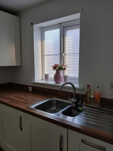 a kitchen counter with a sink and two windows at Anchored Homes in Spalding