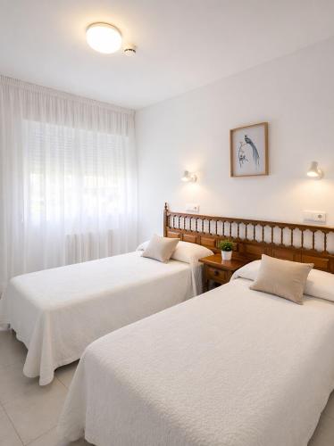 two beds in a hotel room with white sheets at Pensión Rey in Isla de Arosa