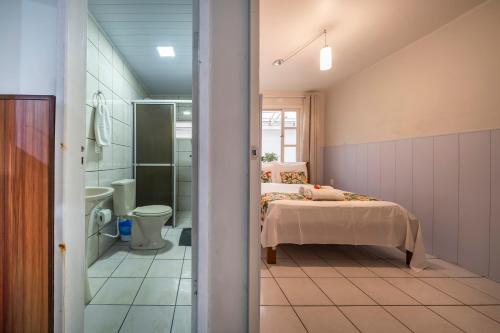a bedroom with a bed and a shower and a toilet at Mares e Flores by OlaMar Bombinhas in Bombinhas