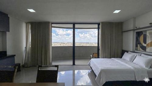 a hotel room with a bed and a large window at Studio Aconchegante com Vista do 33º Andar in Campo Grande