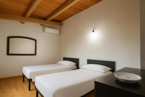 a room with two beds and a table and a mirror at Resort Helenia in Caulonia