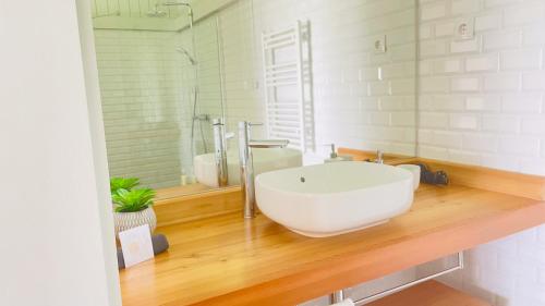 a bathroom with a white sink and a mirror at Abrigos Baleeiros Turismo Rural in Feiteira