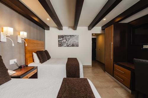 a hotel room with two beds and a television at La Pinta Hotel in Ensenada