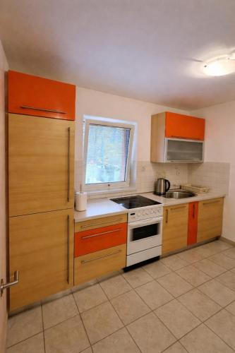 a kitchen with orange cabinets and a white stove top oven at Apartment Seka in Podčetrtek